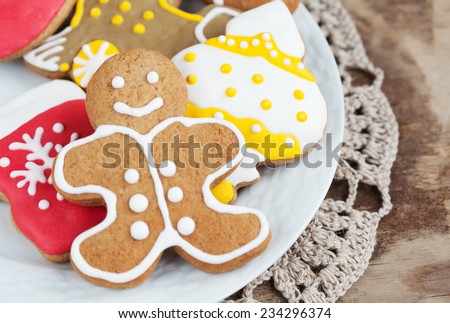 Homemade christmas painted gingerbreads (gingerbread man with buttons, train, fish) on the wooden background. Selective focus and place for text. Toned