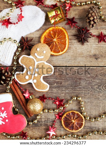Homemade christmas painted gingerbreads (gingerbread man and red boot) on the wooden background with Christmas decorations, cones and candied orange. Selective focus and place for text. Toned