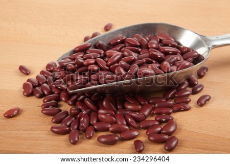 Close up of red kidney beans with scoop on wood table