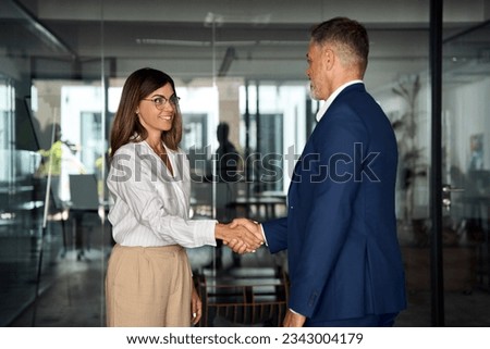 Mature Latin business team of woman and European business man shaking hands as colleagues, partners or employees, signing a contract. Group of people satisfied with results of team work together. Royalty-Free Stock Photo #2343004179