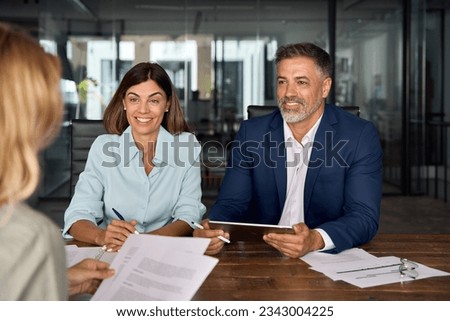 Group of diverse partners mature Latin business man and European business women discussing project with documents at table in office. Team of colleagues professionals business people working together. Royalty-Free Stock Photo #2343004225