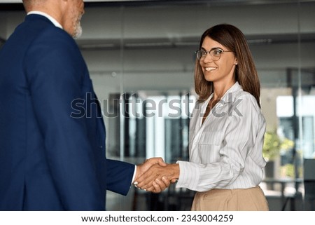 Mature Latin business team of woman and European business man shaking hands as colleagues, partners or employees, signing a contract. Group of people satisfied with results of team work together. Royalty-Free Stock Photo #2343004259