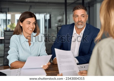 Group of diverse partners mature Latin business man and European business women discussing project with documents at table in office. Team of colleagues professionals business people working together. Royalty-Free Stock Photo #2343004315