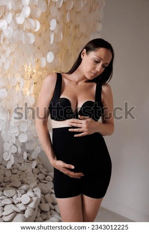 Beautiful pregnant woman in special black pregnancy underwear. Advertisement of comfortable basic pregnancy underpants. Happy brunette girl show her panties in hall. Caucausian thin woman