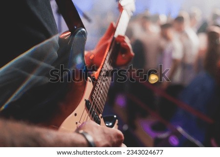 Concert view of an electric guitar player with vocalist and rock band performing in a club, male musician guitarist on stage with audience in a crowded concert hall arena
 Royalty-Free Stock Photo #2343024677
