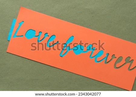 machine-cut paper stencil with the words "love forever" on blue and green paper