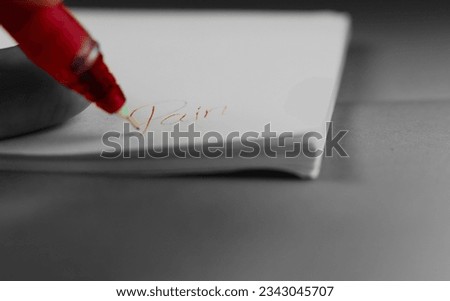 
Writing the word "pain" in English on white paper with a red pen.