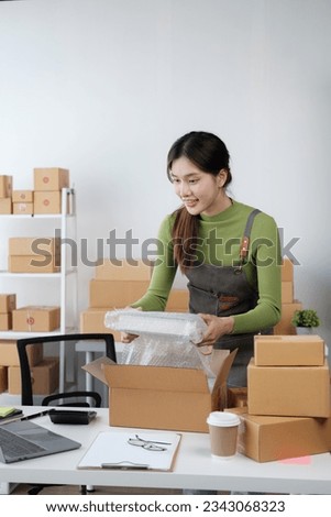 Beautiful young Asian SME shop owner checking product and orders, preparing to the customers. Royalty-Free Stock Photo #2343068323