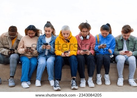 Multiracial group of teen college students ignoring each other looking at mobile phone checking social media. Royalty-Free Stock Photo #2343084205