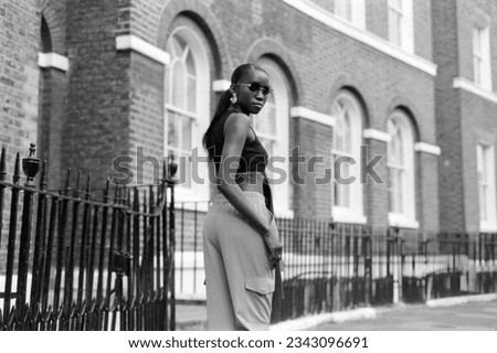 Analog portrait of black young female in front of classic building in London. Image taken with a vintage film camera. Lot of grain.