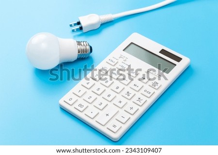 LED bulb and calculator on blue background.