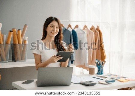 Young Asian woman running online store Startup small business SME, using smartphone or tablet taking receive and checking online purchase shopping order

