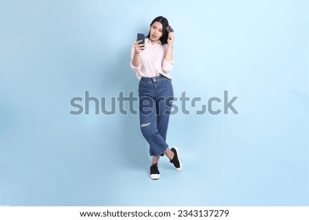The Asian woman in casual clothes standing on the blue background.