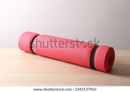 red mat folded into a roll, karemat for camping, on a table