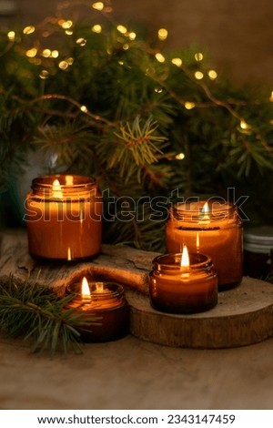 Soy candles burn in glass jars. Comfort at home. Candle in a brown jar. Scent and light. Scented handmade candle. Aroma therapy. Christmas tree and winter mood. Cozy home decor. Festive decoration. Royalty-Free Stock Photo #2343147459