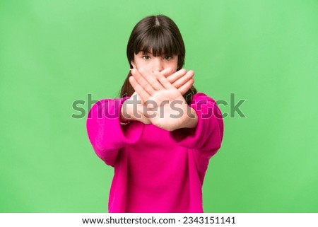 Little caucasian girl over isolated background making stop gesture with her hand to stop an act