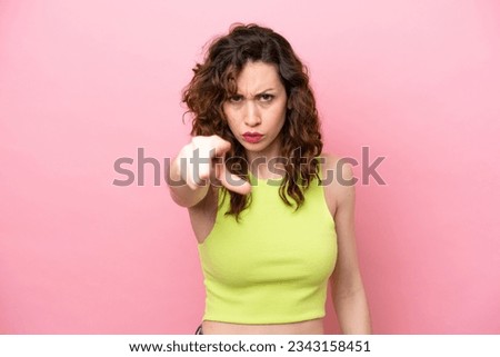Young caucasian woman isolated on pink background frustrated and pointing to the front