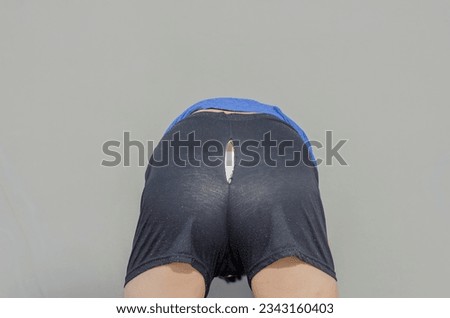 Asian man bending down doing old shorts ripped are torn at the bottom and can see white panties. It because of long time use.