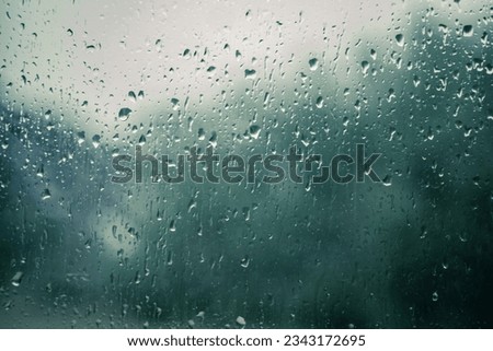 Rain drops on a window with blurry background indicating rainy day Royalty-Free Stock Photo #2343172695