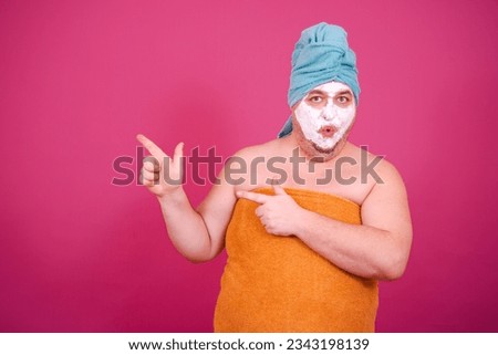 Early morning. Funny fat man enjoys life. The guy wrapped in a towel after a shower poses on a pink background.