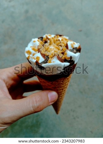 Hand holding an ice cream waffle cone vanila with nuts