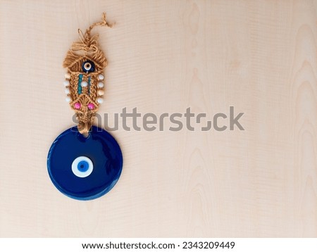 Wicker detailed evil eye bead decorated with coloured beads on a light wooden background