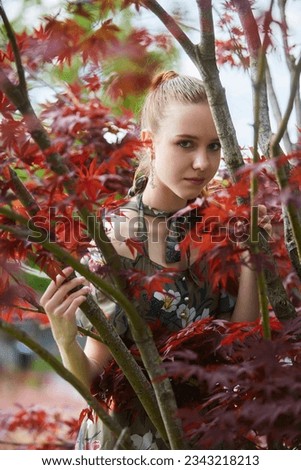 Beautiful young girl near a tree with bright red foliage