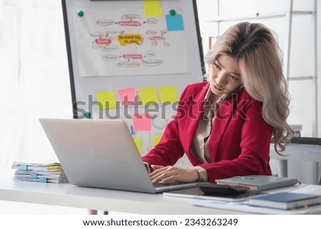 Busy businesswoman at work and talking on the phone looking at laptop screen Frustrated young woman arguing with customer holding a smartphone and being stressed solve business problems.