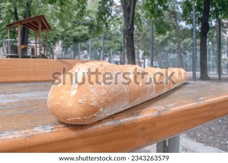 Crispy Baguette: A delightful stock photo capture, featuring a long, crusty baguette placed on a table. Perfect for representing leisure, outdoor dining, and relaxation. conceptual and stock photo.