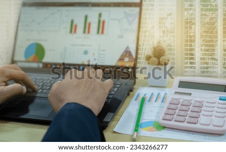 Business man hands typing on laptop computer keyboard,Business marketing graph and Financial analysis chart report , Financial paper charts and graphs on the table.