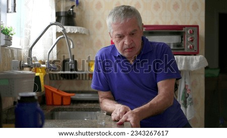 Drunk senior struggling with alcoholism leaning on kitchen sink at home, unhealthy behavior lifestyle in old age. Substance abuse concept Royalty-Free Stock Photo #2343267617