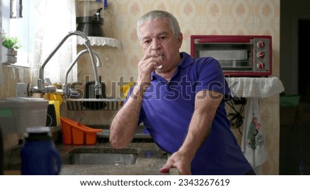 Drunk senior struggling with alcoholism leaning on kitchen sink at home, unhealthy behavior lifestyle in old age. Substance abuse concept Royalty-Free Stock Photo #2343267619