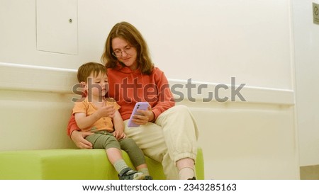 The mother and her baby are in the hospital waiting room, wait for their doctor's visit. Kid boy aged two years (two-year-old)