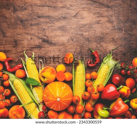 Autumn orange, yellow, red vegetables and fruits set, apricots, cherry tomatoes, pumpkin, corn, etc. on rustic wooden background, top view