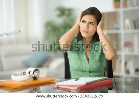 Stressed student complaining about neighbor noise at home Royalty-Free Stock Photo #2343312699
