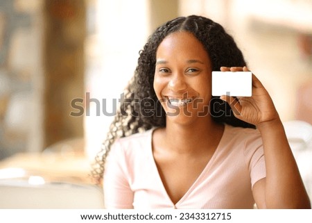 Happy black woman showing blank credit card in a bar terrace