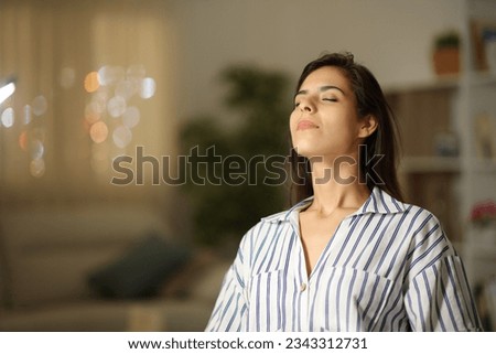 Satisfied woman breathing sitting at home in the night Royalty-Free Stock Photo #2343312731