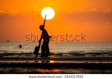 Woman hunting clams on the beach with a homemade bamboo tool, in a beautiful morning.
Photo taken on Dien Thanh beach, Dien Chau district, Nghe An province, Vietnam.