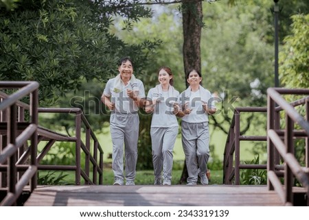 Beautiful Asian woman taking her father and mother to exercise in the park happily, with a smile. Young woman invites parents to exercise, warm family, good health. concept health care life insurance. Royalty-Free Stock Photo #2343319139