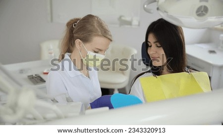 A young brunette girl at the dentist's appointment. Installation of white dental implants. Work of a dentist Royalty-Free Stock Photo #2343320913