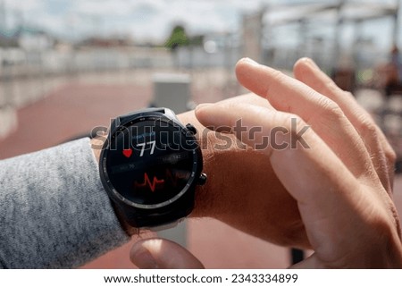 Close-up of smart watch health tracker with the heart rate shown on the screen. Modern stylish and innovation wearable device. athlete checks his heart rate before training at the stadium. heart beat Royalty-Free Stock Photo #2343334899