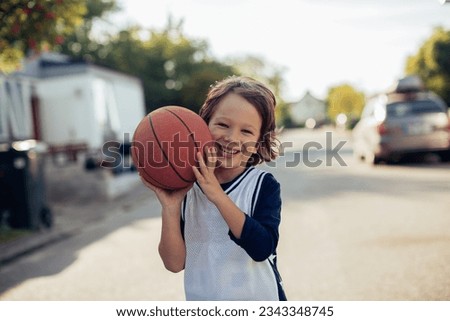Young boy playing with a basketball on the street in the suburbs