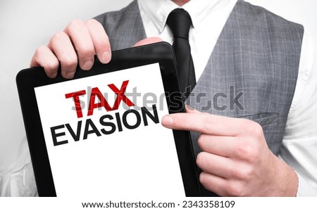 Businessman showing business concept on tablet standing in office TAX EVASION