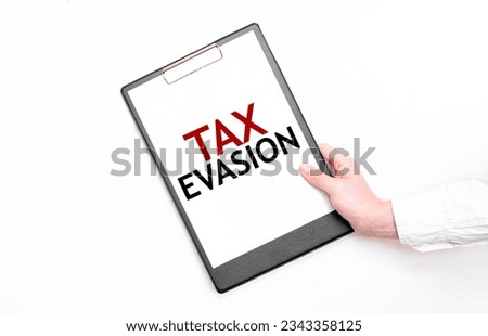 A businessman holds a folder with paper sheet with the text TAX EVASION. Business concept.