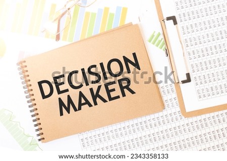 Business up graph on a sheet of craft colour Notepad with DECISION MAKER sign. Notepad on desk with financial documentation