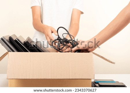 Volunteer hands collect used technology gadgets to charity. Donation box with old laptop computers, phones, tablets. Donate tech equipment, e-waste, electronic waste for reuse, repair, recycle Royalty-Free Stock Photo #2343370627