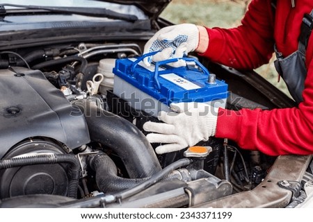 a car mechanic installs a battery in a car. Battery replacement and repair. Royalty-Free Stock Photo #2343371199