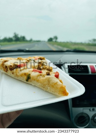 Its a pic of food.picture of pizza in car .
Its pizza piece picture during travel .
Its a delicious food pic