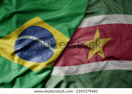 big waving realistic national colorful flag of brazil and national flag of suriname . macro