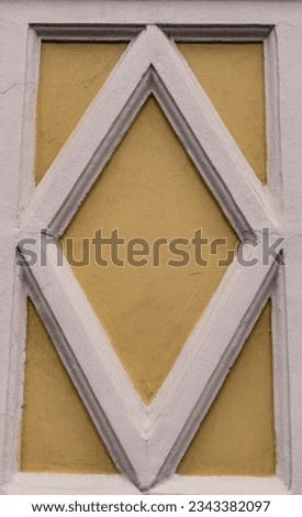A close up photo of a part of th building with bas-relief rhomboid decorative elements in white and light yellow. Royalty-Free Stock Photo #2343382097